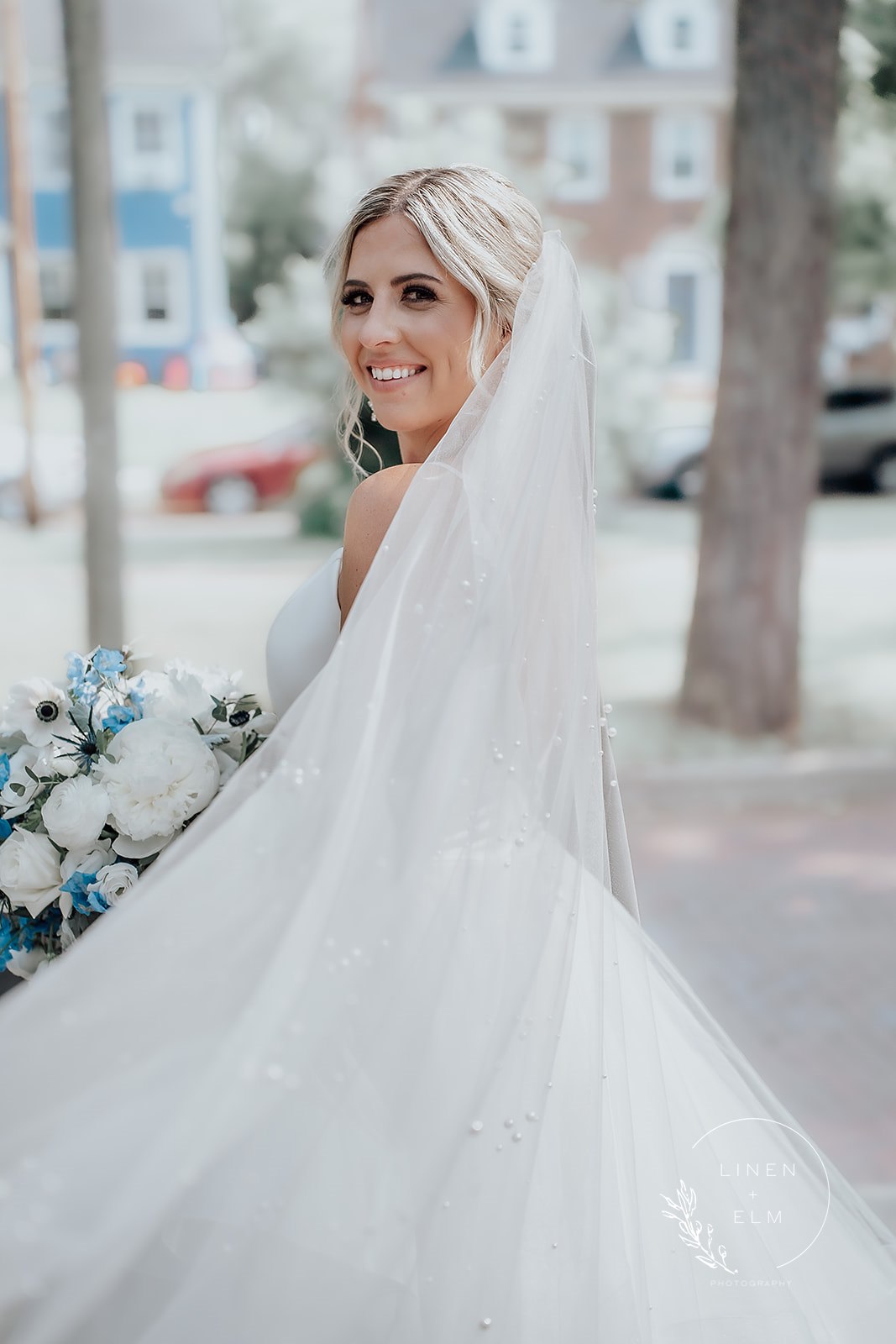 Bride Looking Over Shoulder With Long Veil Outside Cincinnati Wedding Photographer